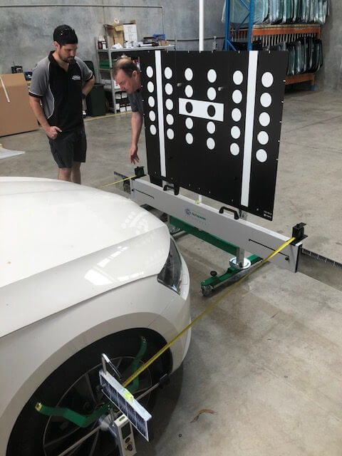 An ADAS-trained technician performing a static ADAS calibration with a target board, alignment rig and wheel bracket in the Buderim workshop