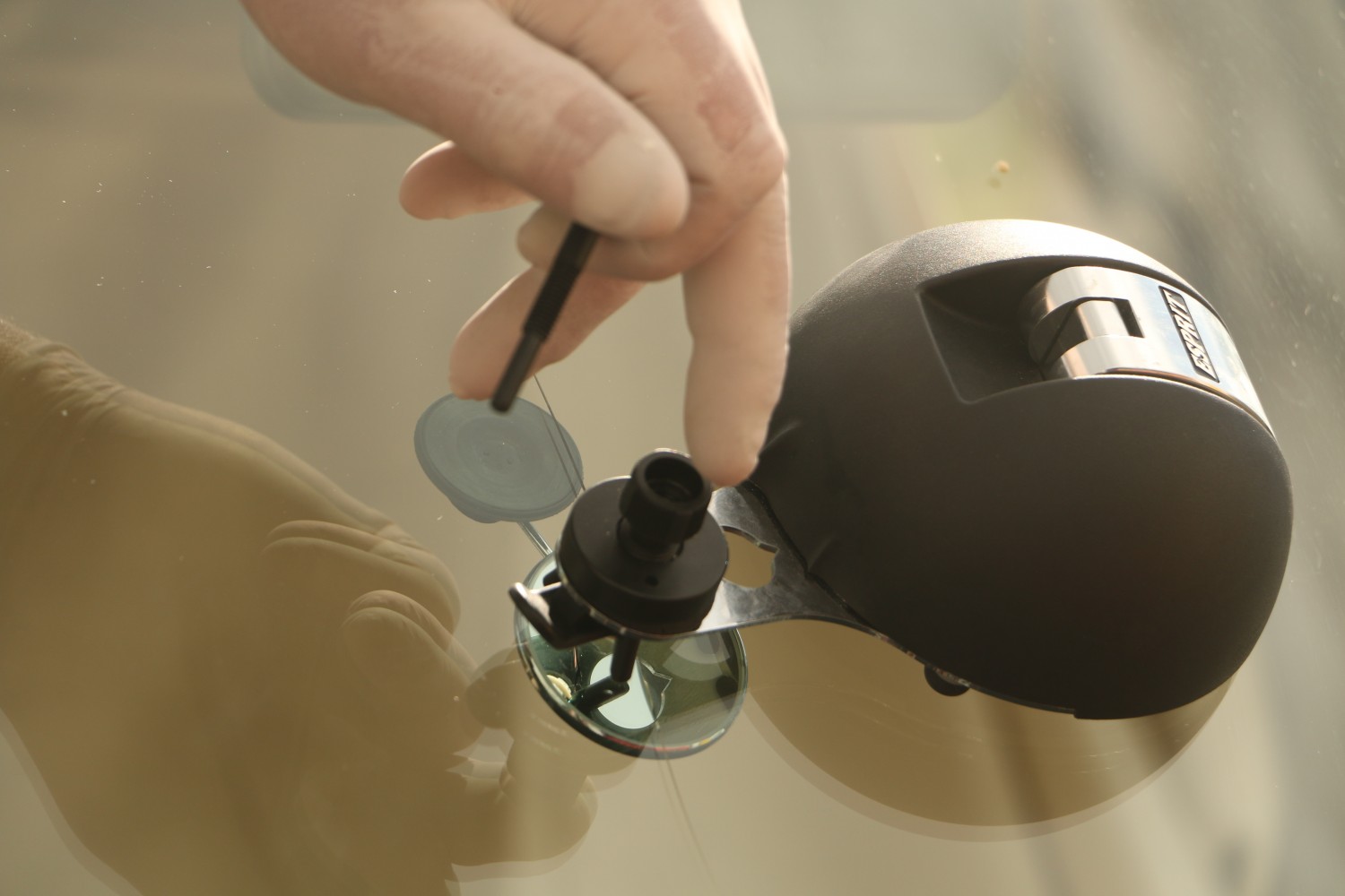 Close-up of the resin injection tool sealing a stone chip on a windscreen
