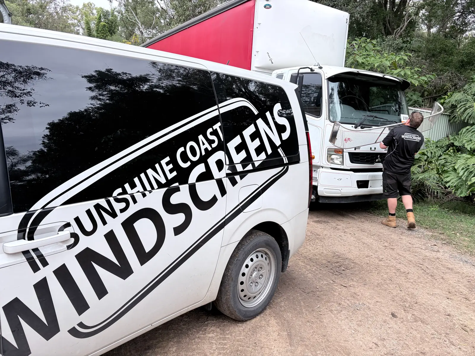 A Sunshine Coast Windscreens van beside a truck having its windscreen replaced