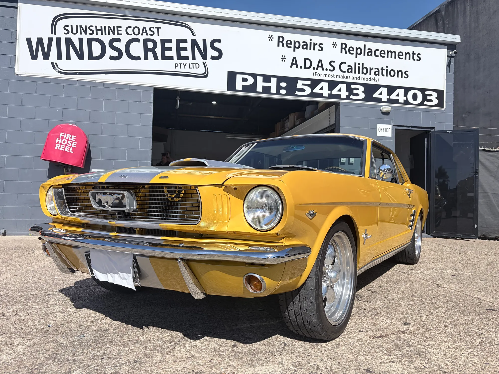 A 1966 Ford Mustang in for windscreen work outside the Sunshine Coast Windscreens shopfront in Buderim