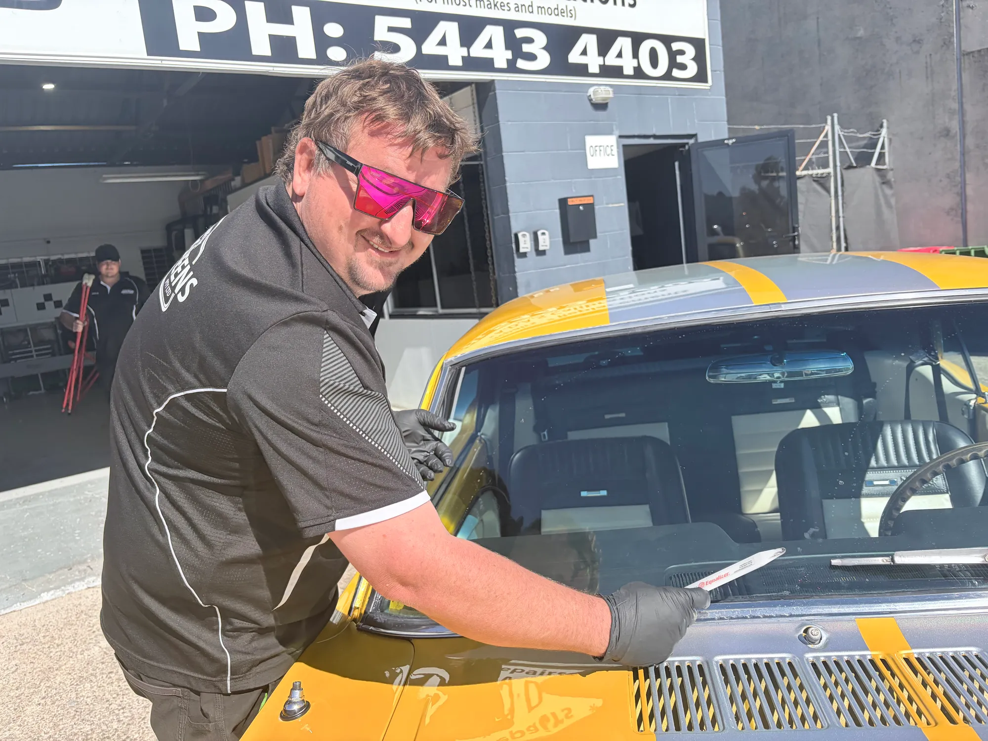 A Sunshine Coast Windscreens glazier working the windscreen out of a 1966 Ford Mustang at the Buderim workshop