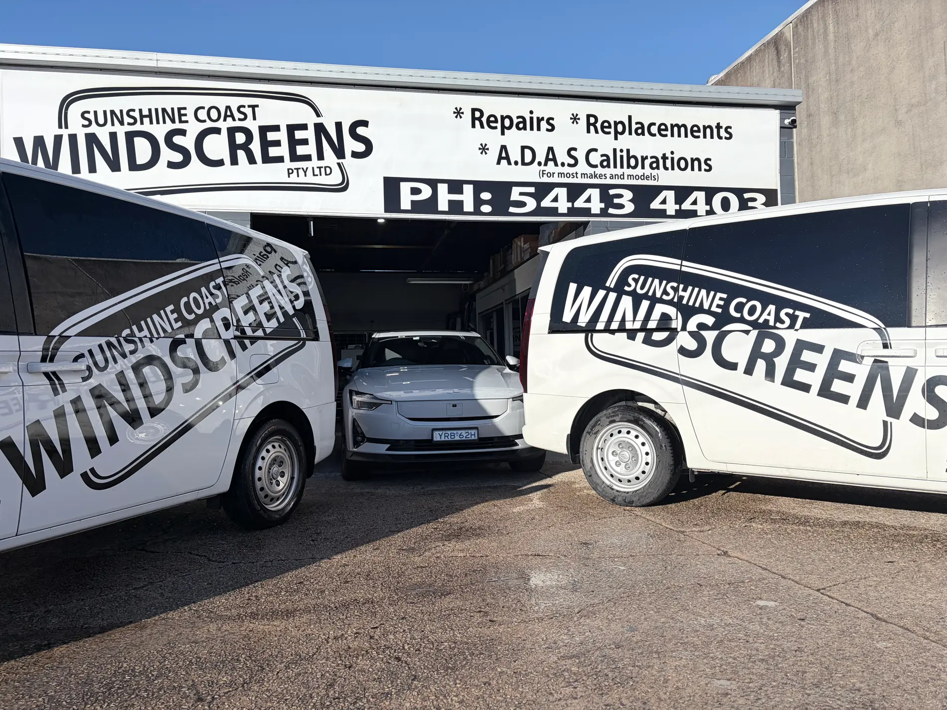 The Sunshine Coast Windscreens shopfront in Buderim with two branded mobile vans and a car in for glass work