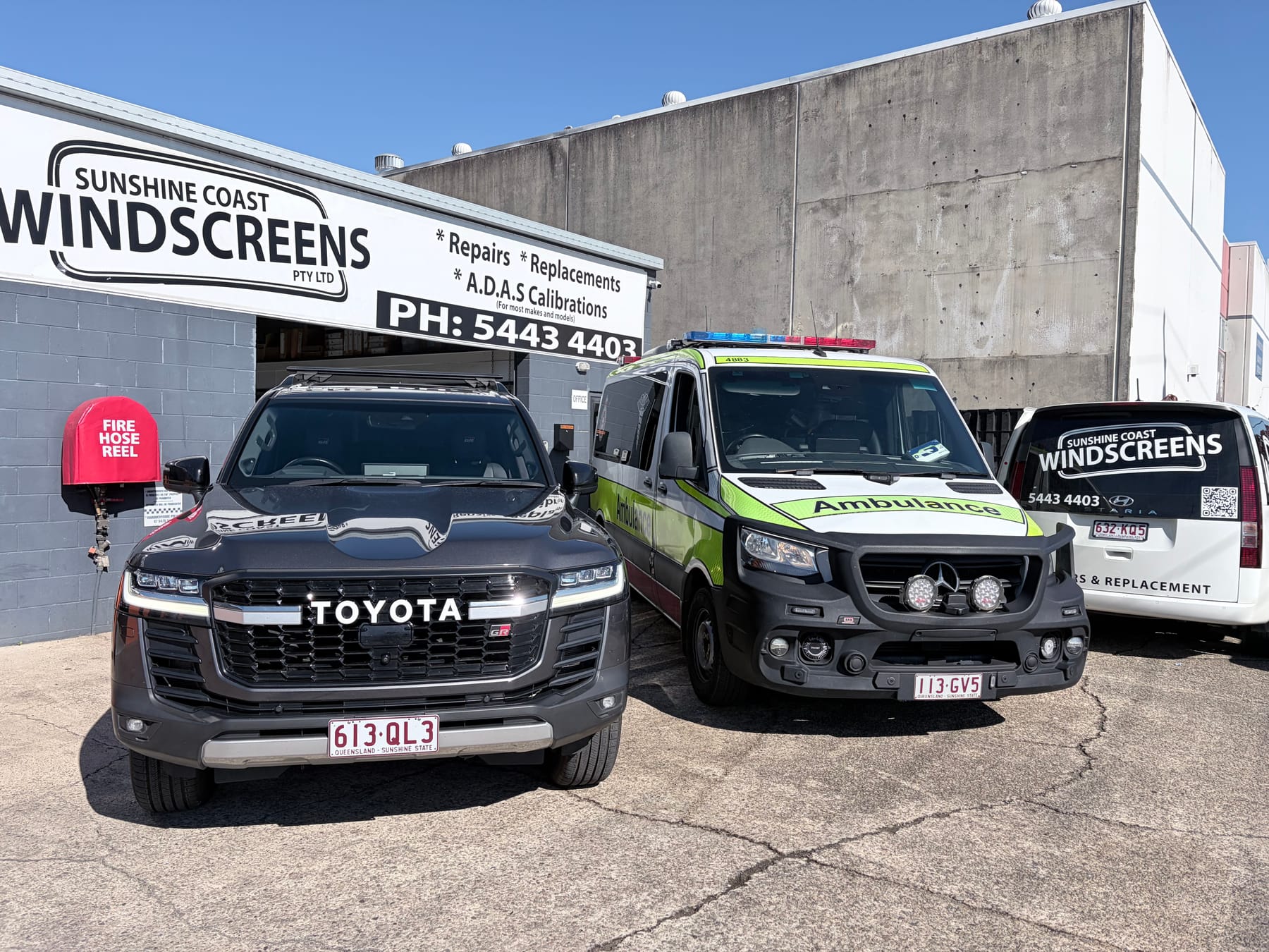 Contact Sunshine Coast Windscreens — the Buderim shopfront, with the fleet and a Queensland ambulance in for glass work