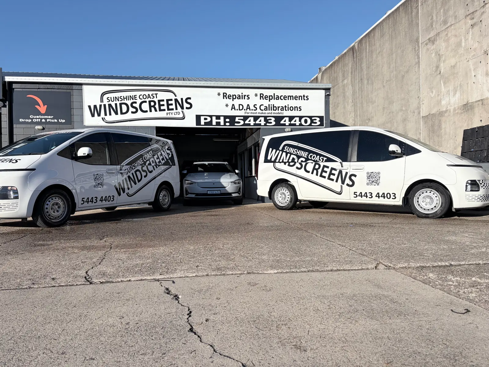 Two branded Sunshine Coast Windscreens vans outside the Buderim shopfront with a car in for glass work