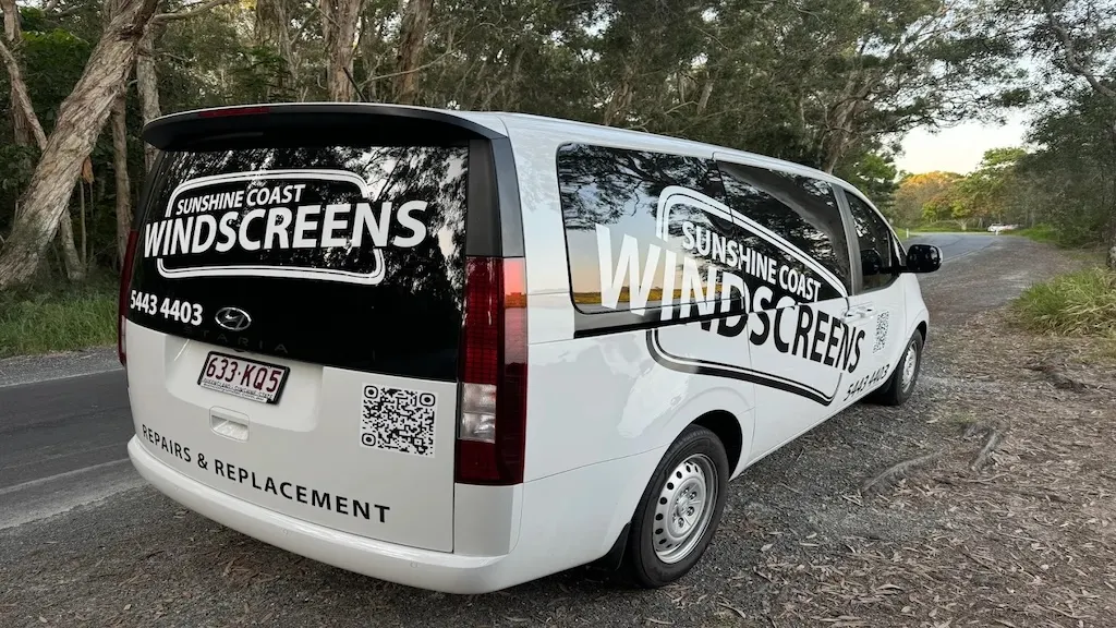 A branded Sunshine Coast Windscreens mobile van on a tree-lined Sunshine Coast road at dusk
