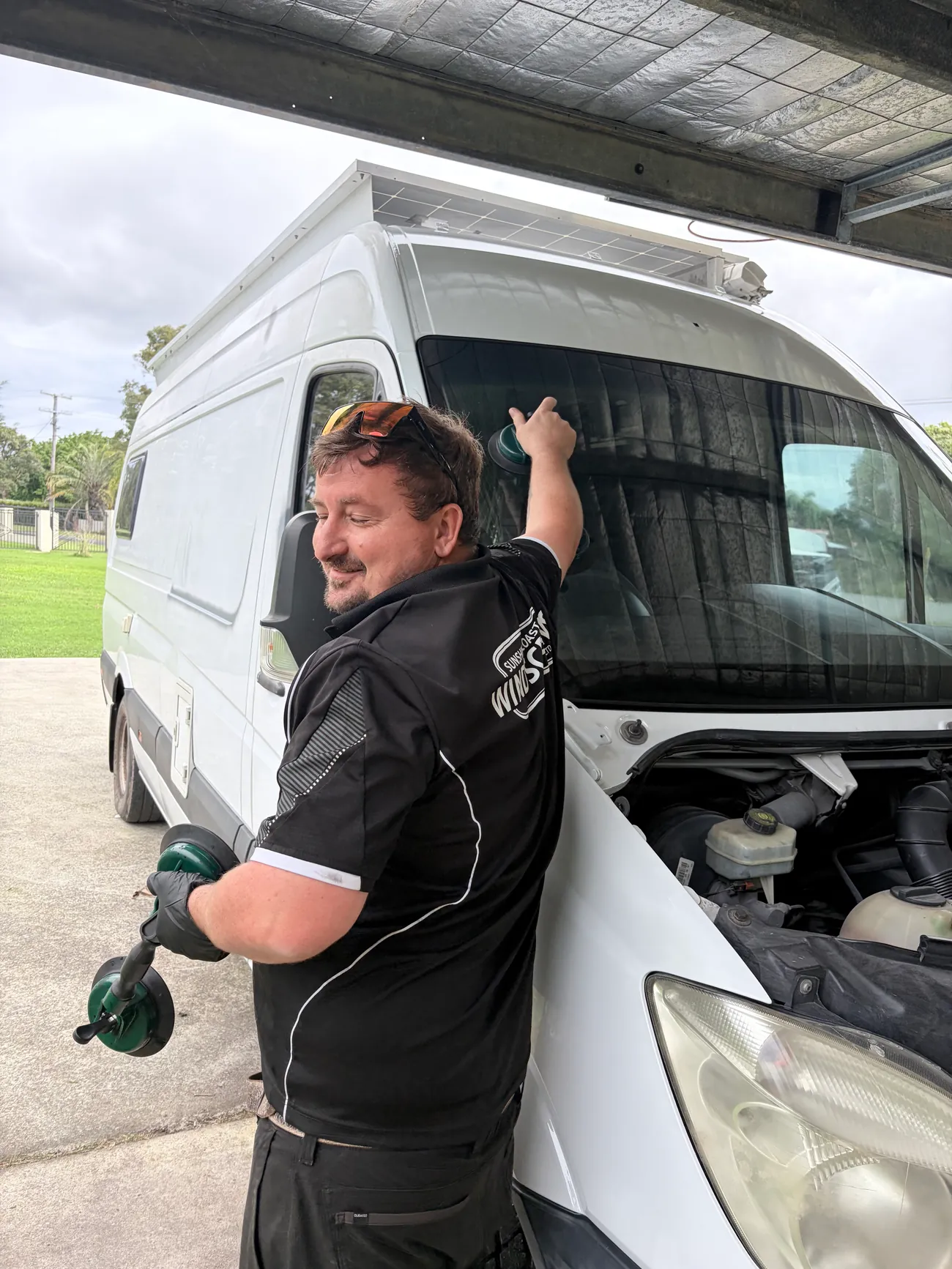 Car side mirror replacement Sunshine Coast — a technician lifting glass out with vacuum cups on a van, side glass sorted on-site